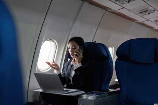 Beautiful Asian businesswoman working with laptop and mobile in aeroplane. working, travel, business concept.