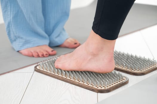 Caucasian woman stands on sadhu boards with therapist support