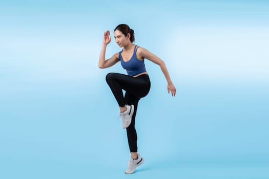 Side view young athletic asian woman on running posture in studio shot on isolated background. Pursuit of healthy fit body physique and cardio workout exercise lifestyle concept. Vigorous