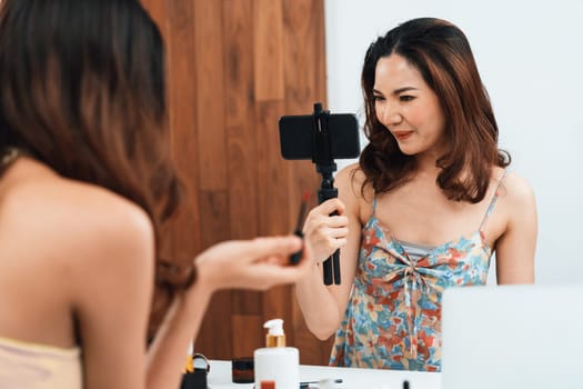 Asian Woman influencer shoot live streaming vlog video review makeup uttermost social media or blog. Happy young girl with cosmetics studio lighting for marketing recording session broadcasting online