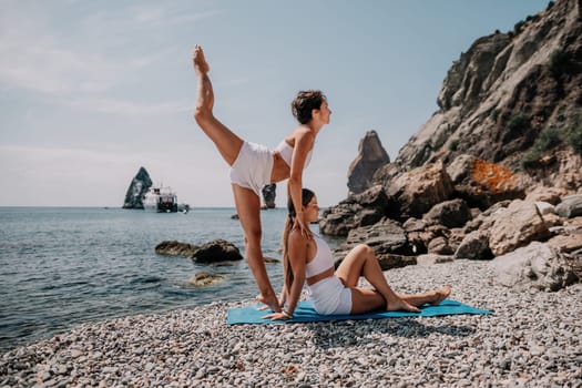 Woman sea yoga. Back view of free calm happy satisfied woman with long hair standing on top rock with yoga position against of sky by the sea. Healthy lifestyle outdoors in nature, fitness concept.