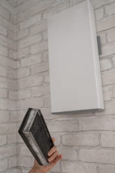 A man changes the filter at the supply ventilation. Gadget for ventilation, disinfection and air purification of the apartment