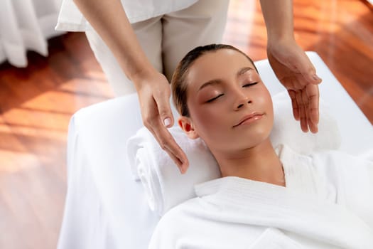 Caucasian woman enjoying relaxing anti-stress head massage and pampering facial beauty skin recreation leisure in dayspa modern light ambient at luxury resort or hotel spa salon. Quiescent