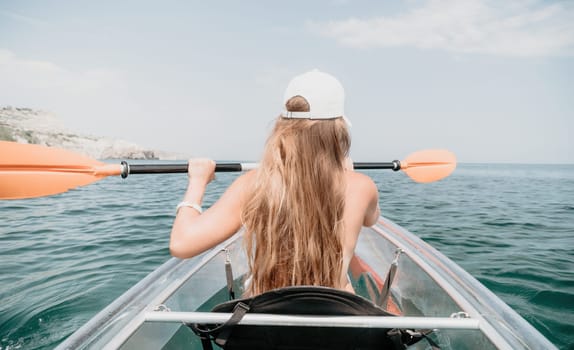 Woman in kayak back view. Happy young woman with long hair floating in transparent kayak on the crystal clear sea. Summer holiday vacation and cheerful female people having fun on the boat.