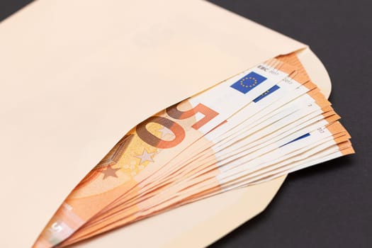 An Orange Paper Envelope with Stack of 50-Euro Banknotes Inside. Salary in Cash. Tax-Free System. Euro Currency. Payments with No Taxes. Orange Paper Money. A Lot of Fifty-Euro Bills