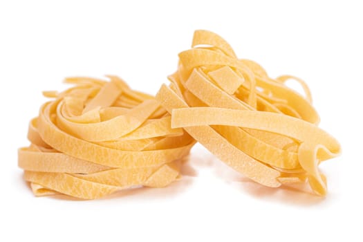 Two Classic Italian Raw Egg Fettuccine - Isolated on White Background. Dry Twisted Uncooked Pasta. Italian Culture and Cuisine. Raw Golden Macaroni Pattern - Isolation