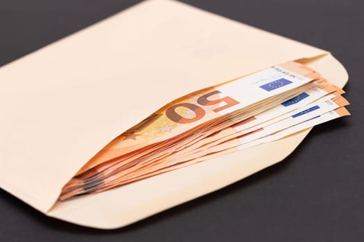 An Orange Paper Envelope with Stack of 50-Euro Banknotes Inside. Salary in Cash. Tax-Free System. Euro Currency. Payments with No Taxes. Orange Paper Money. A Lot of Fifty-Euro Bills