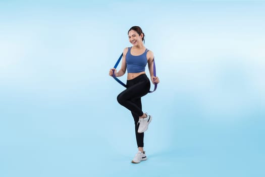 Vigorous energetic woman in sportswear portrait stretching resistance sport band. Young athletic asian woman strength and endurance training session workout routine concept on isolated background.