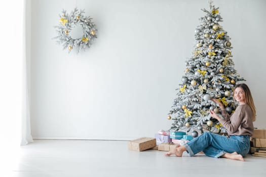 Woman at white christmas tree with gifts for new year