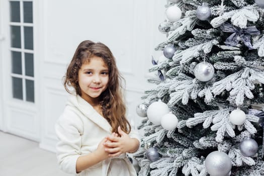 girl at christmas tree with gifts and toys for new year