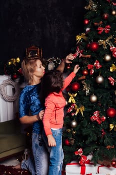 Mom with little girl at christmas tree with gifts and toys