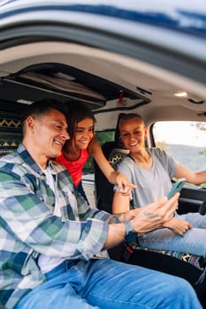 happy family planning on the mobile phone the route through the countryside in their camper van, concept of adventure travel with children and active tourism in nature