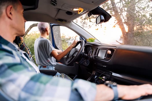 rear view of a woman leaning on the door of her van admiring the landscape in the countryside, concept of couple adventure travel and active tourism in nature