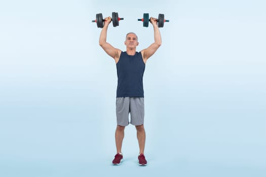 Full body length shot active and sporty senior man lifting dumbbell during weight training workout on isolated background. Healthy active physique and body care lifestyle for pensioner. Clout