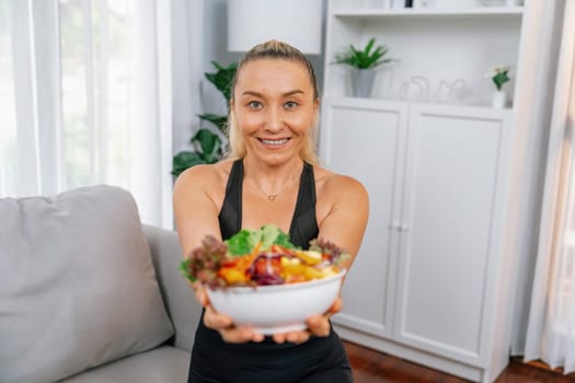 Healthy senior woman in sportswear holding a bowl of fruit and vegetable. Vegan lifestyle and healthy cuisine nutrition for fitness body physique concept. Clout