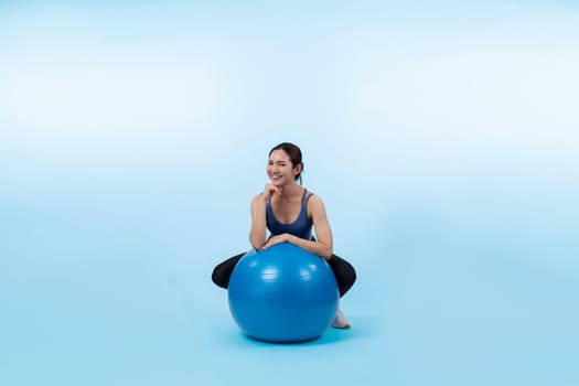 Young attractive asian woman portrait in sportswear with fit ball targeting on abs muscle for effective energetic daily workout routine. Studio shot and isolated background. Vigorous