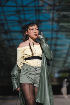 A beautiful Asian woman in shorts and a green leather coat comes out of the subway