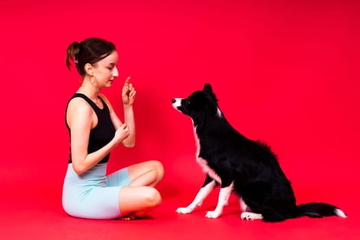 Shot of sport female in leggings with a border collie dog isolated on yellow and red background