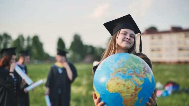 A graduate student poses with a globe in front of her friends