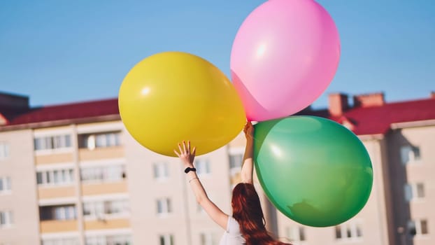 A girl happily poses with large with colorful balloons in the city