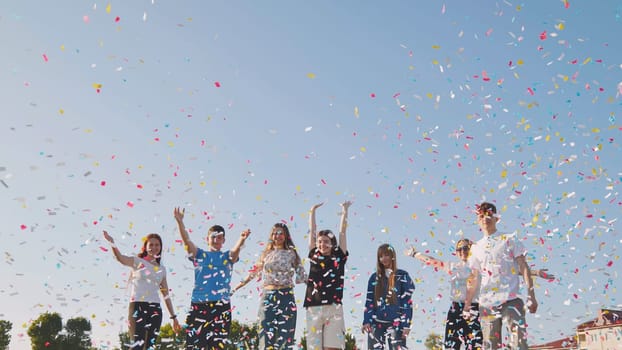 Friends toss colorful paper confetti from their hands