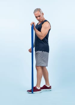 Full body length shot athletic and sporty senior man with fitness resistance band on isolated background. Healthy active physique and body care lifestyle after retirement. Clout