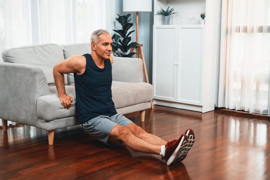 Athletic and active senior man using furniture for effective targeting muscle with push up at home exercise as concept of healthy fit body lifestyle after retirement. Clout