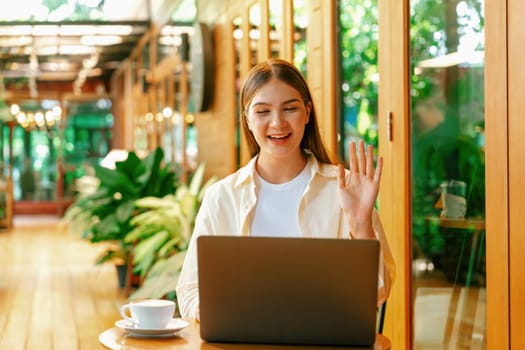 Young woman working on laptop at outdoor cafe garden during springtime, enjoying serenity ambient at coffee shop. Digital nomad freelancer or college student working remotely or blogging. Expedient