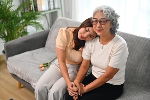 Loving adult daughter holding hands of mature mother showing love and support.