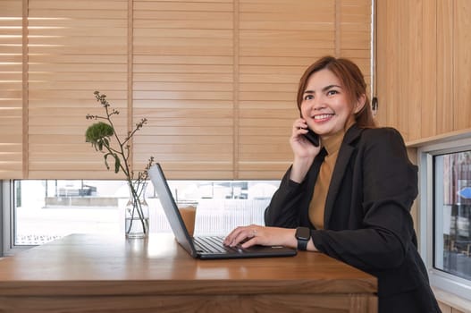 Asian businesswoman smiling happily while talking on mobile phone Business woman calling on smartphone at office business contacts.