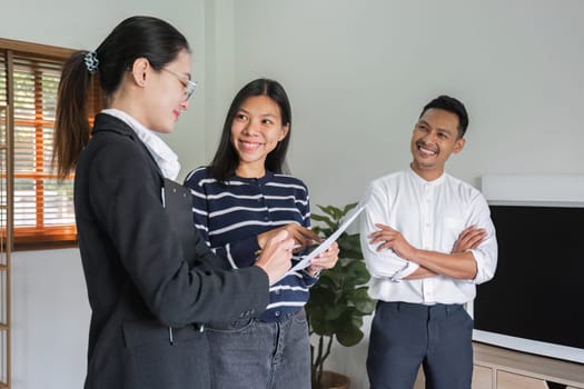 Real estate agents present and advise clients on the decision to sign a home purchase agreement form. Offering mortgage loans and home insurance.