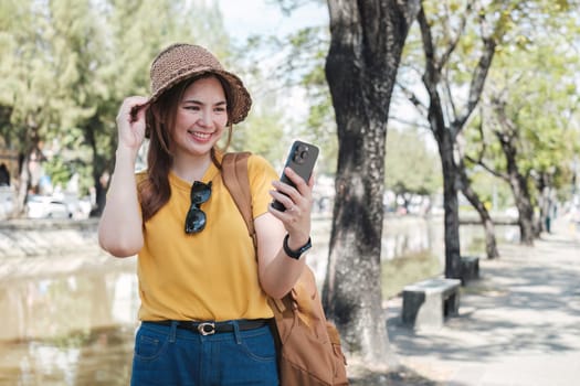 Young Asian tourist walking along city streets and holds a mobile phone on the payment.