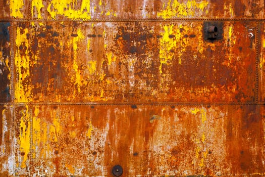 beautifully rusted rivetted sheet metal with leftovers of yellow paint texture and full-frame flat background.