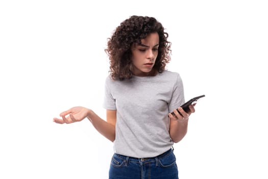 young surprised pretty brunette curly caucasian lady in casual jeans on white background with copy space.