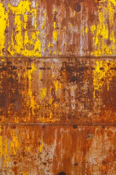 beautifully rusted rivetted sheet metal with leftovers of yellow paint texture and full-frame flat background.