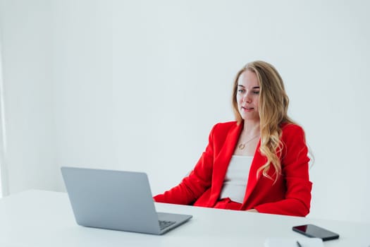 Side view of smiling woman sitting by the table with laptop in office