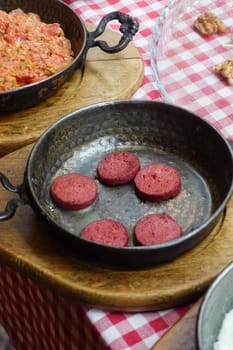 salami sausage in pan served with cheese on table .