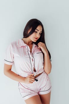 Woman in pajamas standing against a white