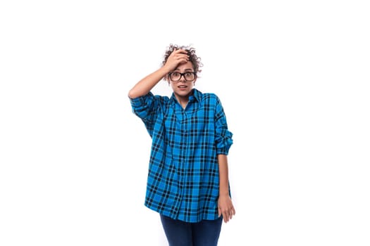 a slender young brunette woman in a loose-fitting blue plaid shirt holds her head.