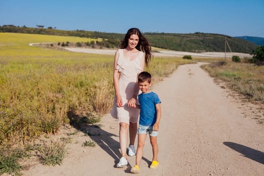 Mother and son walking in nature on the road of a field