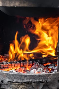 Burning coals and wood in a metal grill for frying meat and vegetables. Cooking on a campfire.