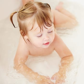 Children, cleaning and water with a baby in the bath for natural skincare, development or hygiene. Kids, bathroom and a happy young toddler girl in a bathtub for health and wellness in her home.