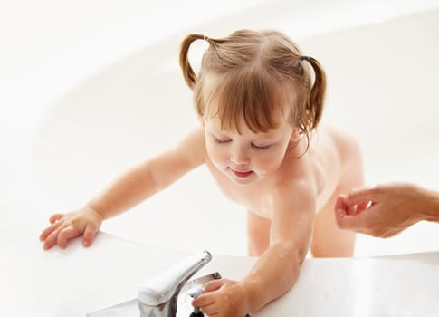 Kids, cleaning and water with a baby in the bath for natural skincare, development or hygiene. Children, bathroom and a curious young toddler girl in a bathtub for health and wellness in her home.