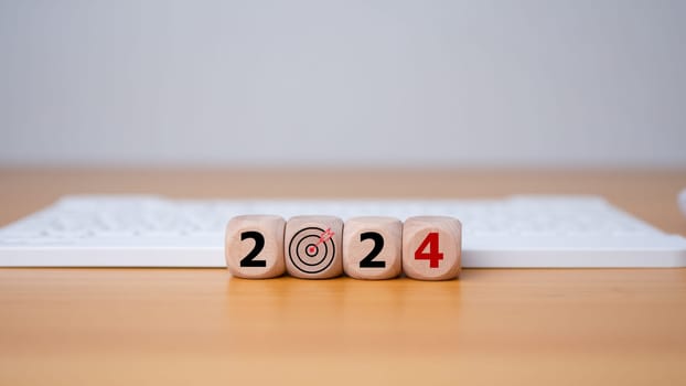 Wooden blocks line the wooden floor and bear the letters 2024, representing the setting of goals for 2024, the idea of a startup. Financial planning, development, business strategy Setting business goals