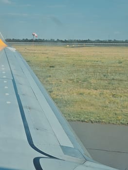 view from the airplane window of the wing and grass during takeoff. vertical photo, soft focus