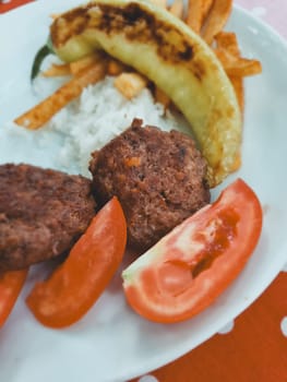 Turkish lunch, meat cutlets, rice and grilled vegetables, soft focus. vertical photo