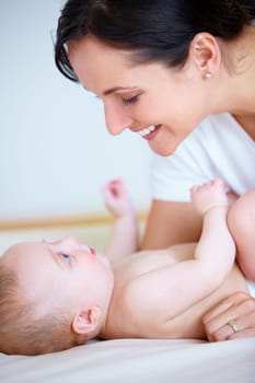 Face, family or smile with a mother and baby closeup on a bed in their home together for bonding. Growth, love or happy with a young woman parent and infant child in the bedroom of an apartment.