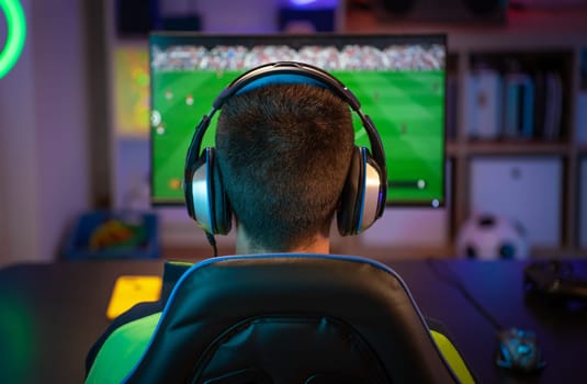 Unrecognizable young man playing sport games on computer at home. High quality photo