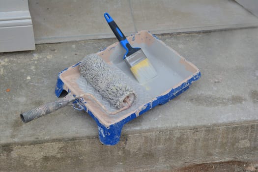 Container with paint roller and brush. Tools for painting.