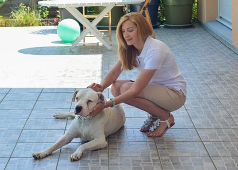 Young blonde girl hugging her dogo argentino